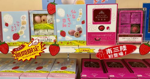 Assorted strawberry-themed Japanese sweets on a store shelf with pastel boxes and strawberry motifs.